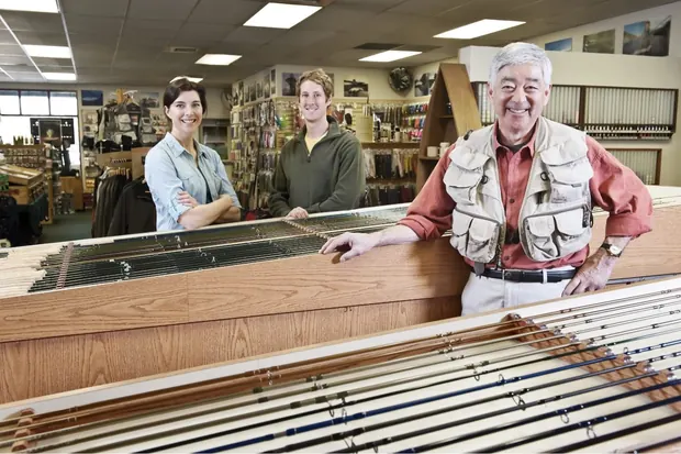 Three shop owners standing behind the counter of their storefront